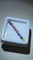 Row of ten round multicolor sapphires in display box
