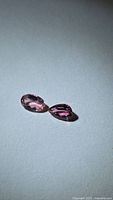 Two oval pink tourmaline gemstones on neutral background
