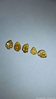 Five carved orange tourmaline stones on neutral background