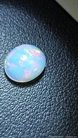 Oval opal showing multicolored flashes on dark background