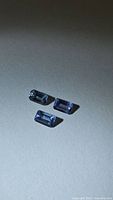 Three rectangular blue-violet emerald-cut tanzanites on neutral background