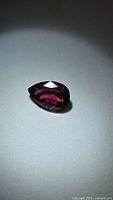 Pear-cut deep purple-red gemstone front view