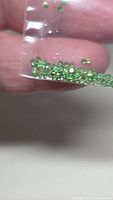 Small loose green tsavorite garnets in plastic bag close-up