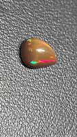 Front view of pear-shaped chocolate opal showing multicolor flashes