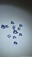 Group of 11 square violet-blue gemstones on white background