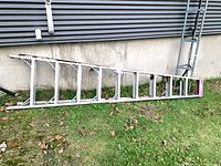 Entire ladder laying on ground beside building