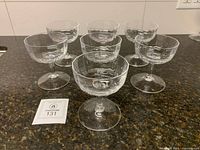 Seven crystal coupe glasses arranged on countertop