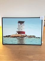 Full view of framed lighthouse painting