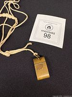Pendant on cord with lot tag visible