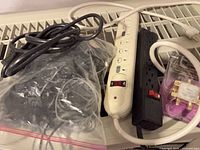 White and black power bars, purple-cased coax splitter, coiled cable and bagged cords on surface