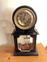 Full view of wooden mantel clock with dial and lower glass showing mercury pendulum