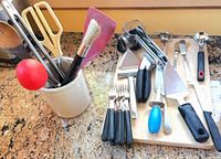 Kitchen gadgets arranged on cutting board and in utensil caddy