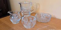 Group shot of four crystal pieces: pitcher, creamer, sugar bowl, square dish