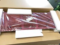 Red three-door storage top in plastic wrap with foam protectors inside original box