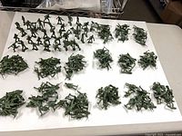 Full lot of green plastic army men spread out on white board