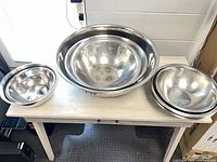 Nested stack of stainless steel mixing bowls on table