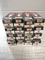 Front view of 16 boxed Champion 18 RV15YC4 spark plugs stacked