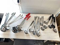 Entire group of 25 stainless ladles and serving spoons on table