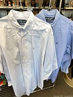 Both shirts hanging front view showing colors and embroidered logos