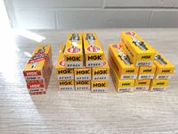 Full group of 17 boxed NGK spark plugs on tabletop