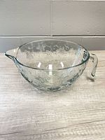 Overall view of embossed glass measuring bowl showing handle and spout
