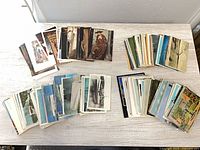 Four stacks of assorted vintage postcards spread on table