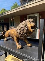 Left front angle of bronze-tone lion figurine on shelf