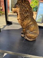 left side view of bronze-finish lion sculpture on shelf