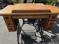 Front view of closed oak cabinet on cast iron treadle base