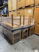 Three massage tables stacked upside down, showing wood frames and black cushions