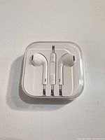 Front view of EarPods in clear case showing earbuds and inline remote