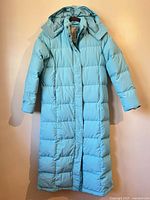 Front view of light blue calf-length puffer coat hanging