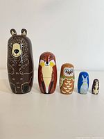 Front view of all five animal nesting dolls lined up largest to smallest