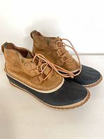 Side view of pair of tan leather and black rubber Sorel duck boots