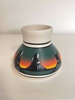 Front view of signed Navajo pottery vase showing teal body, sunset gradient, mountain silhouettes