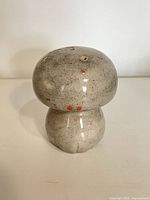 Front view of grey ceramic mushroom shaker showing speckled glaze and overall shape