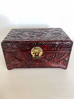 Front view of carved wooden box showing relief design and brass clasp
