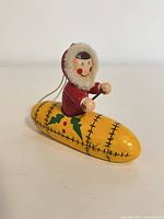 Front view of wooden ornament showing paddling figure and holly-decorated canoe