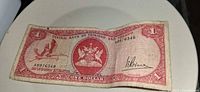Obverse of 1964 $1 Trinidad and Tobago banknote showing coat of arms, bird, serial number A8976348