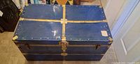 Top view of blue metal steamer trunk with brass straps and lock