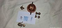 Overhead view of copper kettle, assorted small brass/copper fittings and discs
