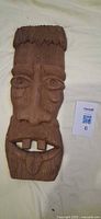 Front view of carved tiki mask showing facial details
