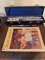 Flute assembled components in open case alongside Flute Method book
