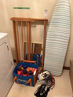 Overall lot showing ironing board, drying rack, tote with supplies, irons and cords