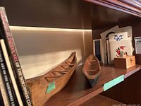 Two cedar model canoes on shelf with cards and books behind