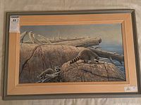 Full view of framed painting showing raccoons on rocky shoreline