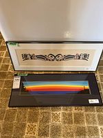 Both framed serigraphs leaning against fridge