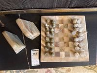 Chess board, pieces set up, two stone bookends visible