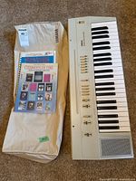 Full view of Yamaha PS-3 keyboard, soft case, stack of songbooks