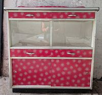 Front view of red starburst arborite kitchen cabinet with glass display section and chrome pulls